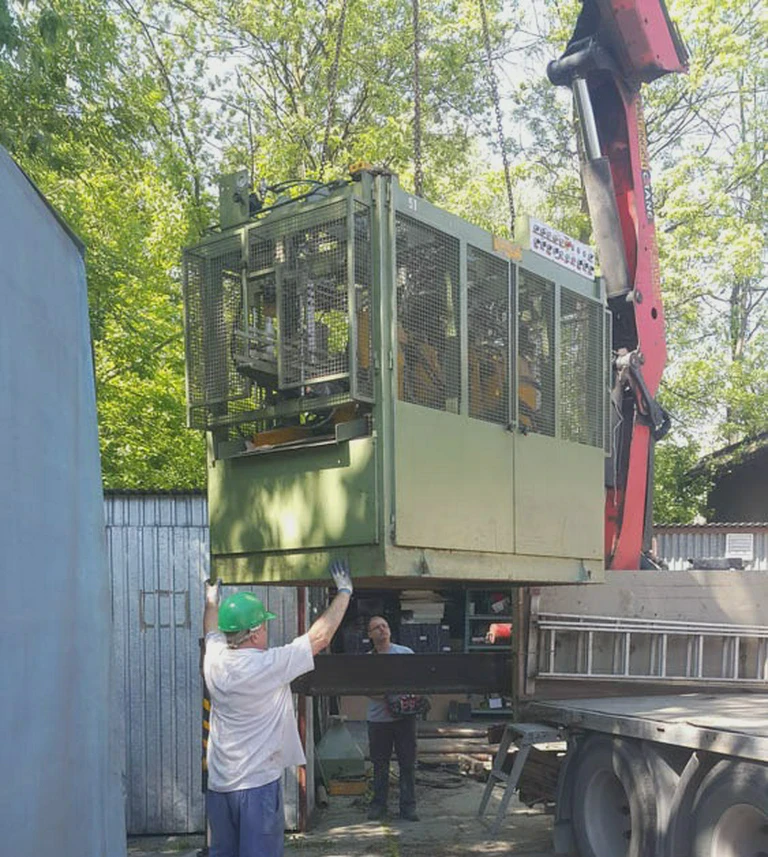 załadunek zielonej maszyny na&nbsp;ciężarówkę