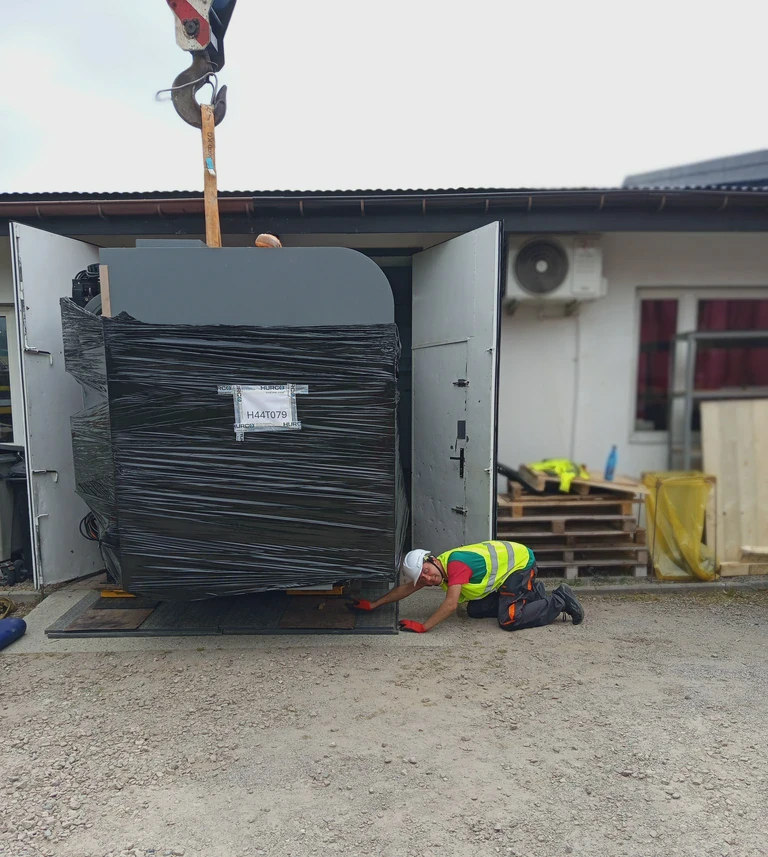 rozładunek czarnej maszyny na&nbsp;placu budowlanym